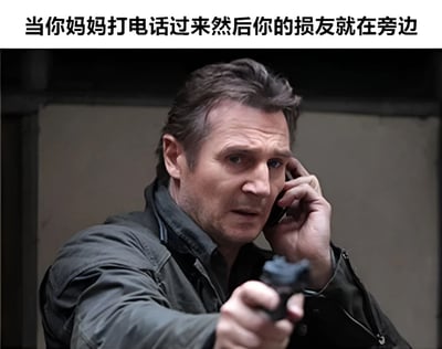 图片展示了演员连姆·尼森一边打电话一边持枪指向的场景，上方配有文字“当你妈妈打电话过来然后你的损友就在旁边”。这个梗图通过连姆·尼森在电影中常见的紧张严肃形象，幽默地表现了当妈妈打电话时旁边有调皮朋友可能捣乱的尴尬又好笑的处境。