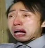 图片中是一名男子的面部特写，他双眼含泪，嘴巴大张，表情极度悲伤，仿佛正在失声痛哭。男子穿着灰色衬衫并系着领带，背景隐约可见木质门框。这张图常被用作表达强烈悲伤或崩溃情绪的表情包。