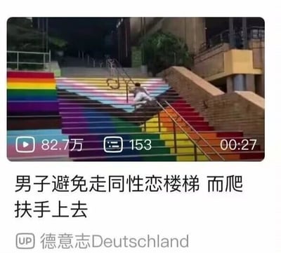 这是一张哔哩哔哩平台的视频截图，画面主体是一段被涂刷成彩虹七色的户外楼梯，一名男子并未正常行走在楼梯台阶上，而是手脚并用地攀爬楼梯的金属扶手。画面下方配有文字“男子避免走同性恋楼梯 而爬扶手上去”，该文案利用彩虹旗作为LGBTQ+群体象征符号的背景，将彩虹色的楼梯调侃为“同性恋楼梯”，把男子爬扶手的行为刻意解读为刻意避开这个带有象征意义的楼梯，以此制造出荒诞、搞笑的反差效果。画面中下部还有视频的播放数据栏，显示该视频播放量82.7万、弹幕数153、视频时长00:27，底部标注了发布该视频的UP主为“德意志Deutschland”。
