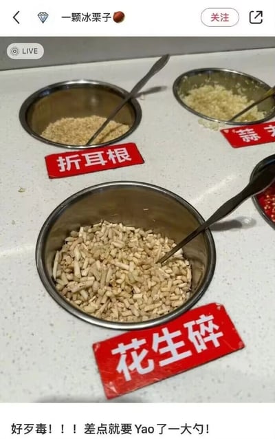 这是一张抖音直播的画面截图，呈现了火锅店的自助调料台场景：台面上摆放着三个配有金属勺子的不锈钢碗，对应红色标识牌“折耳根”“蒜末”“花生碎”。其中标注“折耳根”的碗里是细碎的类似腌渍折耳根的食材，而标注“花生碎”的碗里却装着切成小段的新鲜折耳根，两者形态完全相反，形成强烈反差。图片底部配文“好歹毒！！！差点就要Yao了一大勺！”，这里的“Yao”是“舀”的谐音，表达发布者差点将这碗伪装成花生碎的折耳根舀来当调料的后怕情绪，利用折耳根是部分人群接受度极低的食材这一点，制造出乌龙又搞笑的效果，容易引发有相同饮食偏好的网友共鸣。