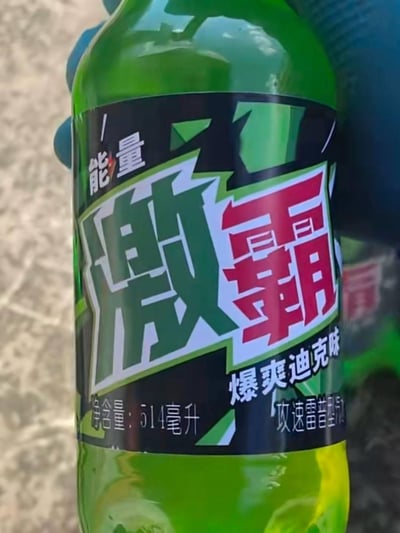 一张绿色能量饮料瓶的特写照片，瓶身上有黑色标签，主要文字为'能量 激霸 爆爽迪克味'，净含量为514毫升。