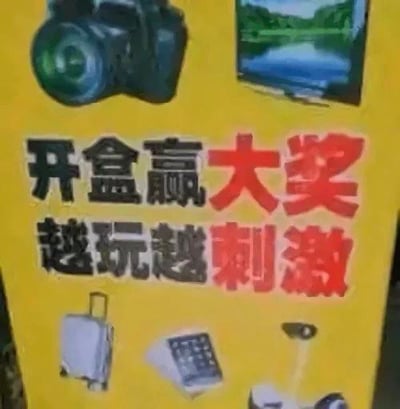 这是一张黄色背景的宣传海报，上方有相机、电视的图片，下方有行李箱、计算器、台灯等物品图案。海报中央以醒目字体写着“开盒赢大奖”（红色）和“越玩越刺激”（黑色），整体风格偏向促销活动宣传，旨在吸引用户参与开盒抽奖类活动。