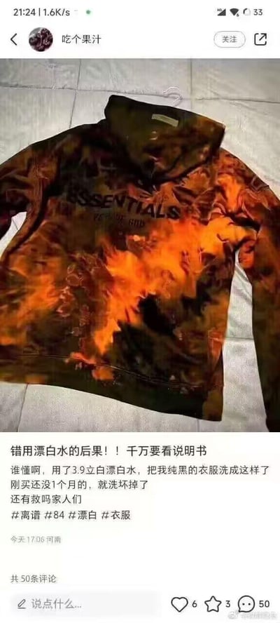 社交媒体用户分享了自己因错误使用漂白水导致黑色卫衣被洗坏的经历。图片中展示了一件原本纯黑的ESSENTIALS品牌卫衣，在使用3.9元的立白漂白水后，变成了橙黑相间的不规则扎染效果。用户表达了对刚买不到一个月的衣服被洗坏的沮丧，并向网友求助是否有补救方法。