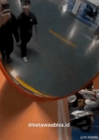 这是一段利用视角错位制造趣味效果的动态图。画面上方的圆形区域中，两名黑衣路人正在正常行走，下方区域则是坐着的人群，由于拍摄视角的巧妙重合，看起来像是上方的路人即将从这个圆形洞口“掉落”到下方的人群里，形成了极具迷惑性又搞笑的视觉错觉。