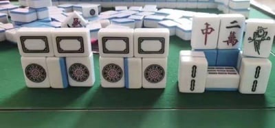 这张图是用麻将牌进行创意摆放的趣味摆拍图，一共呈现三组麻将组合：
1. 左右两组为相同组合：上方两个白板，下方左右是一饼，中间夹着一条，利用“白板”的“白”和“一饼”的“饼”谐音“病”，组合成“百病”，用来调侃80、90后年纪渐长，身体出现各类小毛病的状态；
2. 右侧组合：上方是红中、二万、幺鸡，下方是两个一条和一个二条，红中对应“中”，二万对应“二”，结合起来谐音“中二病”，用来指代年轻人的中二特质，是典型的谐音梗趣味创作。