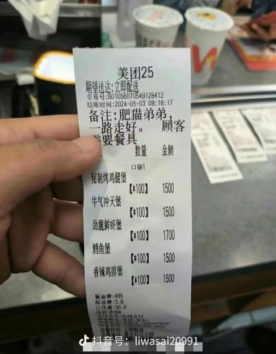 这是一张美团外卖的订单小票实拍图，订单交易号为601056070549128412，结账时间为2024-05-03 09:18:17，期望立即配送。顾客备注写着"肥猫弟弟，一路走好。需要餐具"，同时下单了100份秘制烤鸡腿堡、100份牛气冲天堡、100份劲脆鲜虾堡、100份鳕鱼堡、100份香辣鸡排堡，每份汉堡金额分别为15.00元、15.00元、15.00元、17.00元、15.00元，另含餐盒费495元、配送费3.8元，已优惠30.8元，最终应收8168元。从备注内容推测，这是主人为逝去的宠物"肥猫弟弟"准备的告别餐，特殊的备注与超大的下单量，传递出主人对宠物的深厚情感，让人动容。