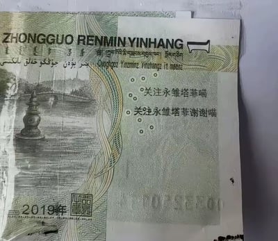 这是一张2019年版的一元人民币纸币，纸币上被添加了黑色文字：'关注永雏塔菲喵'和'关注永雏塔菲谢谢喵'。纸币整体呈现出一定的旧感和褶皱，背景图案为中国传统建筑和风景。