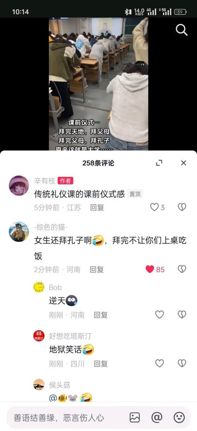 这是一张社交媒体内容截图，上半部分展示了大学教室内的场景，大量学生坐在课桌前低头，配文将传统礼仪课的课前鞠躬仪式调侃为“拜完天地拜父母，拜完父母拜孔子”，感叹这就是大学；下半部分是该内容的评论区，内容发布者辛有枝置顶评论说明这是传统礼仪课的课前仪式感，有网友玩封建时期不让女性上桌吃饭的陋习梗，调侃“女生还拜孔子啊，拜完不让你们上桌吃饭”，这条评论引发其他网友回应，纷纷吐槽该调侃是逆天的地狱笑话。