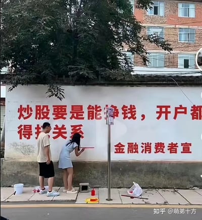画面展示了一男一女在户外白墙上绘制红色标语的场景，标语内容为「炒股要是能挣钱，开户都得找关系」，右下角标注「金融消费者宣」。
这句话用接地气的反讽口吻，调侃炒股赚钱的难度，戳中不少股民的真实体验，用乡村墙绘的形式做金融消费者提示，反差感十足，充满戏谑意味。
