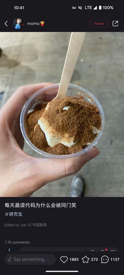 这是一张类小红书风格的社交平台截图，画面上半部分是一只手拿着装有撒满可可粉的奶油类食物的透明小杯，杯中插着一把木质勺子；下半部分是用户的发帖内容，配文为“每天晨读代码为什么会被同门笑”，带有#研究生标签，标注编辑于6月10日中国香港，该帖子获得了1883个点赞、273个收藏、1137条评论，互动量较高。用户以日常食物照片搭配文字，吐槽自己作为研究生，因每天晨读代码被同门嘲笑的困惑，展现了研究生群体在学业日常中遇到的尴尬与不解。