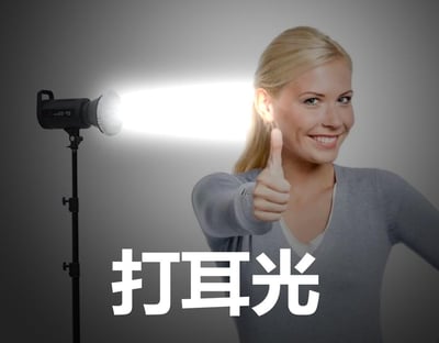 图中一位金发女士面带笑容，伸出手竖起大拇指点赞，她的左侧有一台摄影打光灯正对着她的耳朵方向照射，图片下方配有醒目的文字“打耳光”。这是一个谐音梗玩法，利用“打光（灯光打在耳朵旁）”谐音“打耳光”，通过视觉错位制造出用灯光模拟打耳光的搞笑场景，女士的点赞手势和愉悦表情与“打耳光”的文字形成反差，增添了趣味感。