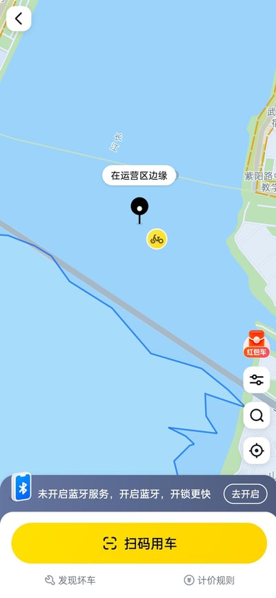 这是一张共享单车应用的竖屏手机界面截图，地图显示车辆的定位位置在长江水域中，还标注了“在运营区边缘”，明显是APP出现了定位错误，把车辆位置错误显示到江面上。界面下方有“未开启蓝牙服务，开启蓝牙，开锁更快”的提示栏，底部有黄色的“扫码用车”按钮，还有“发现坏车”“计价规则”选项，右侧有地图缩放、定位等操作按钮和“红包车”标识，整体是软件BUG的搞笑场景。