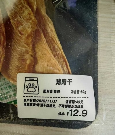 图片为鸡肉干产品的近距离实拍，展示了透明包装内的鸡肉干实物及白色标签。标签上印有产品名称“鸡肉干”、配料表（仅鸡肉）、净含量50g、生产日期2025/11/27、保质期45天，以及注意事项“常温干燥避光，不得饲喂反刍动物”。包装内的鸡肉干呈现自然的棕黄色，纹理清晰可见。
