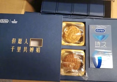 这是杜蕾斯推出的中秋主题创意礼盒，深蓝色礼盒外壳印有古诗「但愿人□ 千里共婵娟」（「长」字位置留空），打开礼盒可见两个月饼和一盒杜蕾斯持久款避孕套。
该礼盒玩了谐音关联的梗：结合中秋「但愿人长久」的美好祝福，与杜蕾斯持久款产品的「持久」属性做趣味结合，将节日氛围与品牌产品巧妙融合，打造出幽默又贴合品牌调性的营销创意。