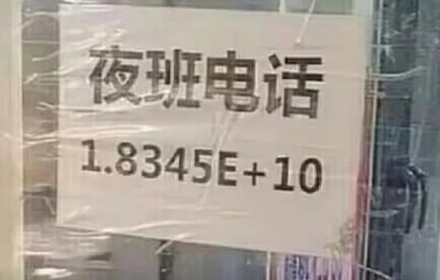 这是一张拍摄的实体标识牌照片，牌子上方写着“夜班电话”，但下方本该标注的手机号码却显示为1.8345E+10的科学计数法格式，显然是制作标识时因表格格式错误，导致11位手机号无法正常显示，变成了类似Excel中的科学计数样式。
这个失误让原本用于应急的夜班电话完全无法被正常拨打，滑稽又离谱，属于工作中低级却搞笑的小错误。