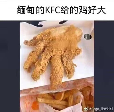 图片展示了一块形状酷似人手的巨型炸鸡，放置在KFC的餐盒中，旁边还有一包薯条。图片上方配有文字“缅甸的KFC给的鸡好大”，通过炸鸡夸张的形状和大小制造幽默效果。
