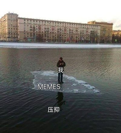 这是一张经过文字改编的情绪梗图，画面中一名真人站在水面上孤立的一小块浮冰中央，人物身上标注着“我”，脚下的浮冰标注“MEMES（梗图）”，浮冰周围的水面标注“压抑”。该图用这个孤寂的场景比喻自己被压抑的情绪彻底包围，只有网络梗图是自己唯一的精神支撑，生动地表达了当代人依靠梗图来缓解内心压抑、寻找情绪寄托的状态；背景是一排老旧的居民楼，暗沉的水面和狭小的浮冰进一步烘托出孤寂、沉重的氛围，让情绪的表达更有代入感。