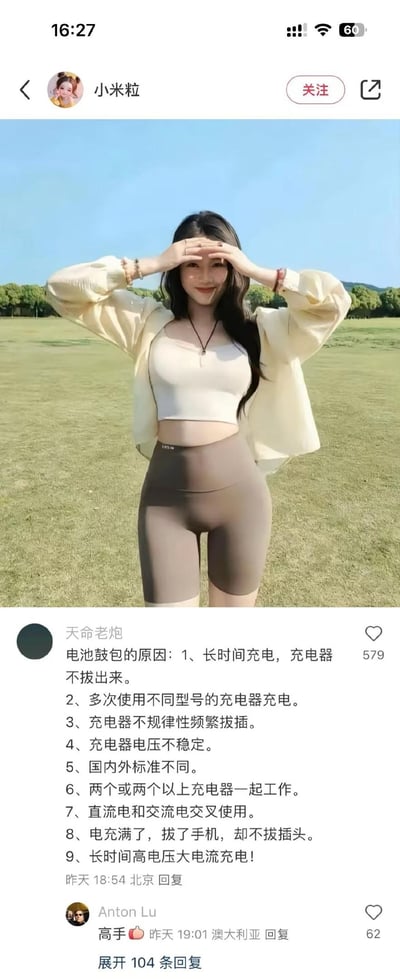 这是一张国内短视频平台的用户动态截图，顶部是博主「小米粒」发布的户外个人照片：她身着短款内搭、浅色防晒开衫与高腰健身短裤，站在开阔草坪上，双手举在额头前方，面带甜美微笑，展现出轻松惬意的状态。下方是用户「天命老炮」的评论，详细列出了9条导致电池鼓包的原因，涵盖充电习惯、充电器使用等多个方面，另一位用户「Anton Lu」回复「高手」，页面还显示有104条更多回复。图片结合了生活分享与数码科普内容，无谐音梗或双关含义，是实用知识在社交平台的互动场景。