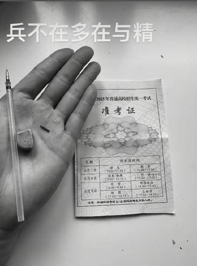 黑白照片中，一只手摊开掌心，下方平放着一张2025年普通高校招生统一考试准考证，旁边有一支钢笔和一块橡皮。画面上方配有文字“兵不在多在与精”，整体构图简洁，通过准考证、文具与手部动作的结合，搭配文字形成“强调质量而非数量”的隐喻，可能用于调侃或励志高考备考场景。