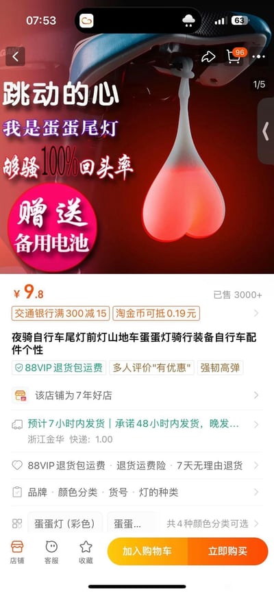 这是一张电商平台的自行车配件商品详情页截图，展示了一款造型猎奇的自行车尾灯——“蛋蛋尾灯”，造型模仿男性睾丸，宣传语以“够骚100%回头率”为卖点，主打个性化骑行装备。商品售价9.8元，已售出3000+件，赠送备用电池，支持交通银行满300减15、淘金币抵扣等优惠，发货地为浙江金华，店铺为7年好店，提供88VIP退货包运费、7天无理由退货等售后保障，共有4种颜色分类可选。该商品靠低俗趣味的奇葩造型吸引眼球，满足骑行爱好者追求个性化、高回头率的需求。