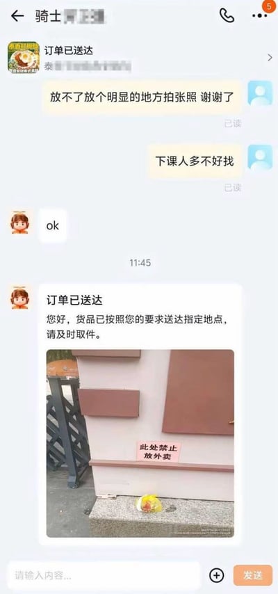 这是一张外卖平台聊天记录的截图，展示了顾客与骑手之间的有趣互动。顾客因下课后人多难找外卖，特意嘱咐骑手“放不了放个明显的地方拍张照 谢谢了”，并补充“下课人多不好找”。骑手回复“ok”后，在11:45发送了“订单已送达”的通知，内容为“您好，货品已按照您的要求送达指定地点，请及时取件。”，同时附上一张照片——外卖被放在一个标有“此处禁止放外卖”红色标识的建筑物旁的地面上。整个对话充满了 situational irony（情境讽刺），骑手虽然“照做”将外卖放在了“明显位置”，却恰好违反了现场的禁止规定。