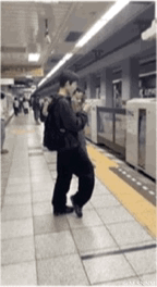 这是一段GIF动态图，呈现了地铁站台的场景：一名身着黑色服饰的男子站在站台边缘，由于他的腿部与身旁的立柱在视觉上恰好重合，形成了‘下半身消失’的视觉错位效果，制造出滑稽有趣的反差感，让人忍俊不禁。