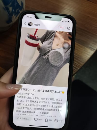 这是博主「月宝宝」的一条日常PLOG动态，图中博主穿着的灰色衣服胸部位置有特殊凸起设计，视觉效果十分尴尬。博主在文案里分享了自己的社死经历：当天家里来了客人，她超级热情地抱着宝宝迎接、跑着端水果，招待完客人打扫卫生后照镜子才发现衣服的尴尬之处，瞬间崩溃，直呼「换个星球再见了家人们」，充满无奈又好笑的社死氛围。