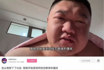 这是一张短视频平台的视频截图，画面中是一位披着粉色毛巾的肥胖男子，身处室内环境，背景可见窗户。男子正对着镜头诉说自己的经历，画面配有字幕“我就开始受到同性恋群体的骚扰”，视频下方的简介栏也重复了“自从我胖了了以后 我就开始受到同性恋群体的骚扰”这句话。男子的表情看起来带着无奈与苦恼，整体内容是个人生活经历的分享，不存在双关、谐音梗或暗示类内容。