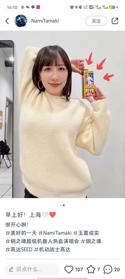 这是日本歌手玉置成实的社交媒体动态截图，她身穿米白色竖纹针织衫，面带甜美微笑，一只手臂搭在脑后，双手共同展示一款带有“36年坚持 鲜榨”字样的饮品包装，并用红色箭头突出指向该饮品。动态配文“早上好！上海❤️🤍 很开心啊！”，还附带了#美好的一天 #玉置成实 #钢之魂超级机器人热血演唱会 #高达SEED 等话题，显然是她来上海参加相关演唱会期间，分享在当地的日常瞬间，状态轻松愉悦。图中没有双关、谐音梗或暗示内容。