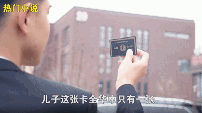 图片中一名身着黑色西装的男子正手持一张黑色卡片展示，背景为一栋红褐色建筑。左上角有“热门小说”字样，画面下方配有字幕“儿子这张卡全华中只有一张”。该场景是“龙王赘婿”系列广告的经典片段，体现了“卑微赘婿-身份揭露”的爽文式剧情套路，通过稀有物品（全华中唯一的黑卡）暗示角色隐藏的尊贵身份，为后续打脸逆袭情节铺垫。