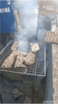 这是一则充满趣味的视觉错位动态GIF。画面中，拍摄角度让下方的石头看起来像是放在烤架上被烤制的食物，而真正的食物则摆在旁边的台面上。当“烤架上的食物”掉落时，观众才发现这是视觉错觉，制造出强烈的反差感，带来搞笑的观看体验。