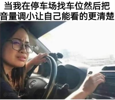 这是一张图文结合的搞笑表情包，采用顶部配文加下方实景图的形式。顶部配文吐槽了很多驾驶员都有过的无逻辑迷惑行为：在停车场找车位时会下意识调小车内音量，认为这样能看得更清楚。下方实景图为一名戴眼镜的女性坐在汽车驾驶座上，手扶方向盘，正在操作中控台调小音量，脸上是困惑又认真的神情，精准还原了这一普遍又没有合理逻辑的生活化行为，很容易引发大众的共鸣。