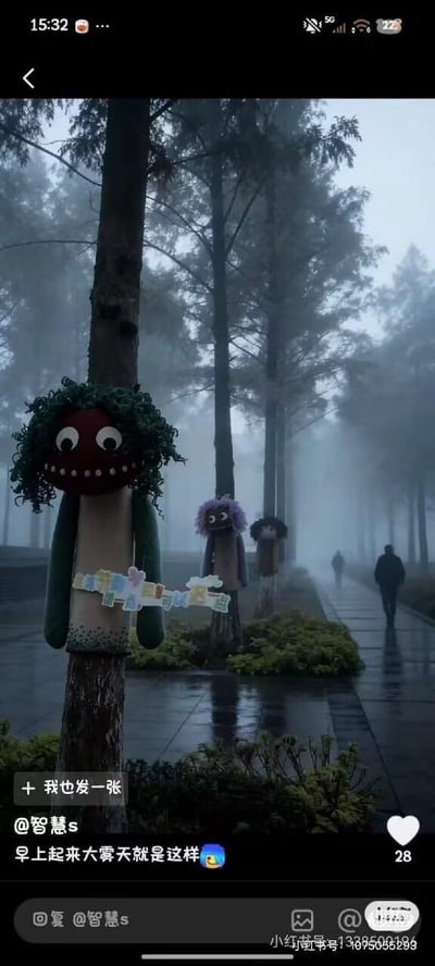 一张社交媒体截图，展示了一个大雾弥漫的早晨场景。画面中有一条湿漉漉的林荫小道，道路两旁的树干上装饰着几个手工制作的玩偶，它们有着夸张的面部表情和彩色的身体。远处有模糊的人影在雾中行走，增添了神秘氛围。图片下方有用户配文“早上起来大雾天就是这样”并带有一个无语表情符号。