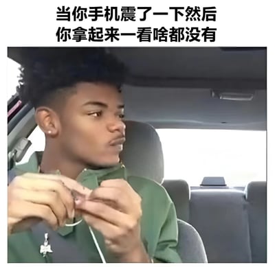 图片展示了一个坐在车内的年轻人，他正拿着手机线，表情困惑地看向一边。图片上方配有文字：'当你手机震了一下然后你拿起来一看啥都没有'，幽默地表现了人们常有的'幻听手机震动'的经历。