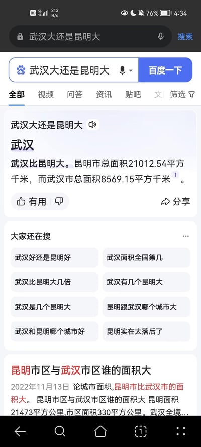 这是一张手机端百度搜索“武汉大还是昆明大”的结果页面截图，页面中出现了明显的信息矛盾：顶部的搜索结果给出数据“昆明市总面积21012.54平方千米，武汉市总面积8569.15平方千米”，却得出“武汉比昆明大”的错误结论；下方另一篇2022年的内容则指出“论城市面积，昆明市比武汉市的面积大”，同时还展示了“大家还在搜”的相关联想词，体现了用户对两座城市面积、发展对比的关注度。