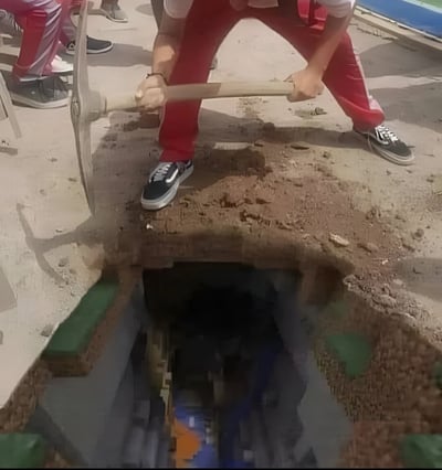 图片中一名身穿红色裤子和黑色运动鞋的男子正弯腰用铁锹挖掘地面，铁锹插入泥土中，地面已被挖出一个方形洞口，洞口下方隐约可见砖砌结构和深色空间，疑似通向地下通道或窖穴。背景中还有其他穿着红色裤子的人站立围观，地面为水泥材质，整体场景像是在户外进行挖掘作业。