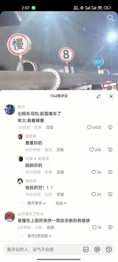 图片上半部分为模糊场景，可见三个路牌：红色圆形'慢'字牌、红色圆形'8'字牌、蓝色圆形'OUT'字牌，背景有大型管道。下半部分是社交媒体评论区截图，显示1162条评论，热门评论包括'出租车司机:前面堵车了'及回复'牢大:我看哪塞'，还有'塞塞你的'、'脱脱你的'、'他妈的甘!!!'等调侃内容，另有评论提及'上厕所突然一笑给夹断的救赎感'，整体充满网络幽默氛围。