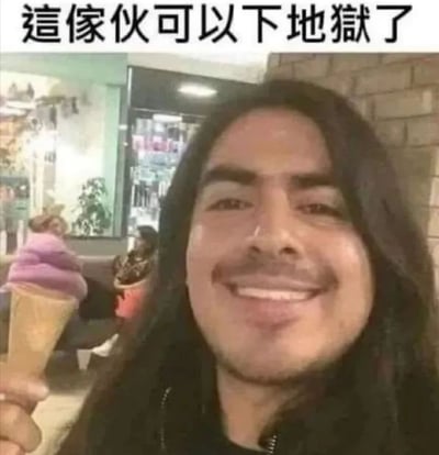 图片中是一位长发男子在冰淇淋店中手持冰淇淋甜筒，脸上带着夸张灿烂的笑容。男子表情看起来非常开心，背景中可以看到其他冰淇淋产品和店内环境。图片上方有一行醒目的中文文字：'這傢伙可以以下地獄了'，形成一种幽默的反差效果。