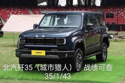 这是一张户外拍摄的北京BJ40硬派越野车的实拍图，车辆停放在铺有绿色草坪的户外场地，背景是红色座椅的看台和遮阳棚。图片下方添加了玩梗文字，将车型名称谐音为「北汽歼35（城市猎人）」，还配上了类似MOBA类游戏的战绩数据「35/1/43」，模仿击杀/死亡/助攻的格式，制造出汽车跨界游戏圈的反差搞笑效果。
谐音梗说明：将北京BJ40的名称谐音为「北汽歼35」，结合游戏战绩的呈现方式，属于汽车爱好者结合游戏文化的趣味玩梗。