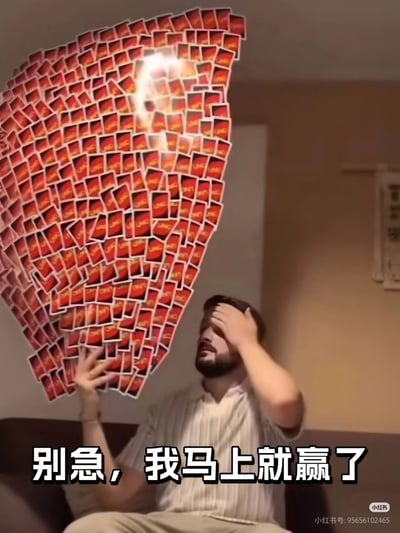 这是一张经过PS合成的搞笑表情包，画面中留着胡须的白人男子坐在室内，一只手抬起捂住半张脸，另一只手举着数量夸张到离谱的一大把红色背面的扑克牌，牌堆还添加了发光特效进一步凸显数量的不切实际，图片底部配有醒目的白色粗边黑色文字“别急，我马上就赢了”，整体营造出当事人明明处境离谱、胜算极低却依然嘴硬不肯认输的反差搞笑效果，常被用来调侃各类逆风局势下硬撑场面的行为。