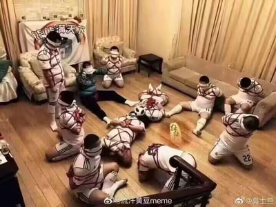 这是一张荒诞搞笑的P图改编作品，场景设定在室内客厅中：多名穿着运动服饰的真实人物被白色绳索以类似捆绑的方式束缚，呈现出跪坐、躺卧、半蹲等不同姿态，面部大多被遮挡；人群中还混入了一个经典的熊猫头网络表情包角色，同样被“绳索”束缚着躺在地上。背景的布幔上印有“熊能满天下”的字样，地面上还有一块写着“熊猛”的标牌，整体画面将真实场景与网络表情包进行混搭，充满无厘头的整活感，没有双关或谐音梗，纯以荒诞的合成效果制造笑点。