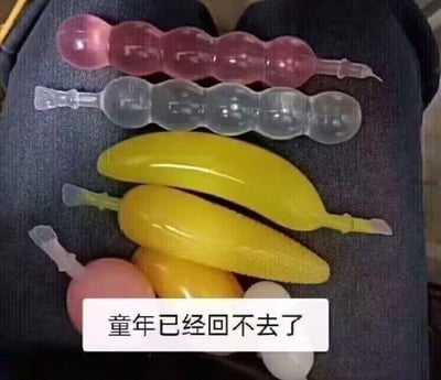 图片中展示了多款充满童年回忆的造型吸吸冰（果冻类零食），包括糖葫芦串状、香蕉状、玉米状、桃子状等不同样式，它们被放置在深色裤腿表面。图片下方有一个白色文字框，里面写着“童年已经回不去了”。这些造型独特的吸吸冰是许多80、90后的童年常见零食，以吸食的方式食用，图中文字直接抒发了对童年美好时光的怀念与感慨，没有双关、谐音梗或其他暗示内容。
