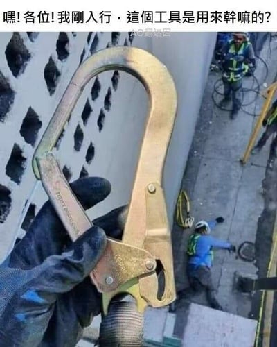 这是一张带有黑色幽默的讽刺梗图：前景是一只戴着手套的手，拿着高空作业用的安全钩（安全带挂钩）；画面上方配有文字“嘿！各位！我刚入行，这个工具是用来干嘛的？”；背景则是真实的高空作业事故场景，一名工人摔落在地面，另外两名工人在旁目睹。图中用刚入行新人询问安全装备用途的场景，搭配同时发生的坠落事故，以极端直观的方式强调这个安全钩是用来防止高空坠落、保障作业人员生命安全的装备，通过强烈的反差制造黑色幽默的效果，也侧面警示了安全装备的重要性。