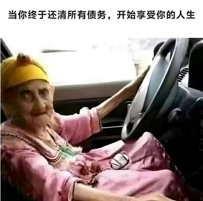 图片展示了一位 elderly person 坐在汽车驾驶座上，双手握着方向盘，戴着黄色头巾，穿着粉色衣服。图片上方配有文字：'当你终于还清所有债务，开始享受你的人生'。这张图片通过展示一位 elderly person 开车的场景，幽默地表达了许多人可能需要到老年才能还清债务的社会现象，暗示了现代生活中债务压力的长期性。
