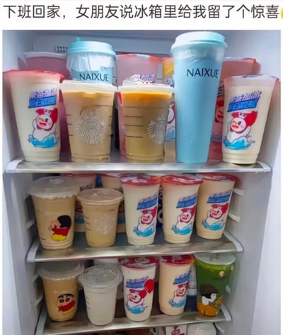 图片展示了一个塞满各种奶茶杯的冰箱内部，上层和下层货架均整齐摆放着来自蜜雪冰城、星巴克、奈雪的茶等品牌的奶茶。顶部配有文字“下班回家，女朋友说冰箱里给我留了个惊喜”，以幽默的方式呈现“惊喜”其实是大量奶茶的有趣场景，展现了情侣间轻松搞笑的日常互动。
