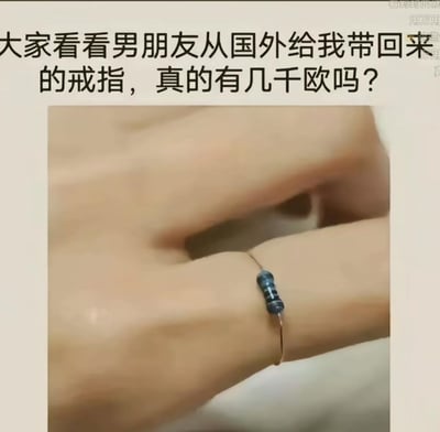 这是一张搞笑图文作品，图中展示了女生的手指，上面戴着一个“改装戒指”——将一个色环电阻固定在细金属环上充当戒指的主石。配文“大家看看男朋友从国外给我带回来的戒指，真的有几千欧吗？”玩了谐音梗：“几千欧”既可以指价值几千欧元，也可以指电阻的单位欧姆，这个“戒指”本质是廉价的电子元件，和“几千欧（欧元）”的昂贵礼物设定形成巨大反差，制造出荒诞搞笑的效果。
