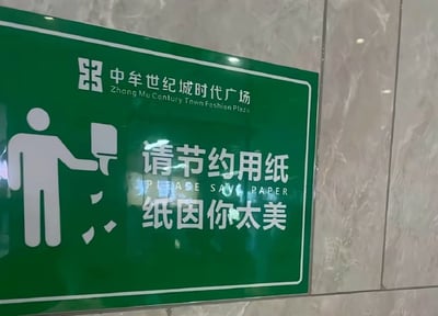 这是一张厕所节约用纸提示牌的照片，牌子正中央写着“请节约用纸 纸因你太美”，借用了著名网络梗“鸡你太美”的空耳和走红语句。原词“只因你太美”被巧妙改写为“纸因你太美”，形成谐音梗，意思是鼓励人们节约用纸，因为纸“太美”了不舍得浪费。

这类二次创作利用网络热梗，增加提示语趣味性与传播性，使得原本枯燥的文明标语变得有梗且年轻化，适合分享和拍照打卡。

**双关/谐音梗说明**：此图的“纸因你太美”即“只因你太美”的谐音，也是“鸡你太美”梗的直接应用。