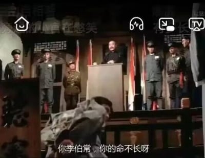这是一张老战争题材电影的视频截图，画面呈现了一个类似训话的正式场景：一位男性站在讲台后方，数名身着军装的人员整齐地站在讲台两侧，画面下方有一个人弯腰背对镜头。画面底部配有字幕“你季伯常，你的命不长呀”，传递出警告的语气；画面顶部带有“官在憋笑”的水印，还有视频播放的相关图标，整体氛围严肃，该截图常被用作梗图来调侃或表达警告意味。