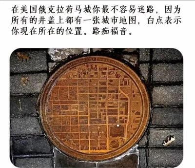 图片上方为文字说明，内容为“在美国俄克拉荷马城你最不容易迷路，因为所有的井盖上都有一张城市地图，白点表示你现在所在的位置。路痴福音。”；下方是一张实拍照片，展示了一个圆形井盖嵌在黑色砖铺路面中，井盖表面雕刻有详细的城市网格地图，地图上有一个明显的白色圆点标记。整体呈现了一种实用有趣的城市设计，旨在帮助路人辨别方位，尤其对方向感较差的人十分友好。