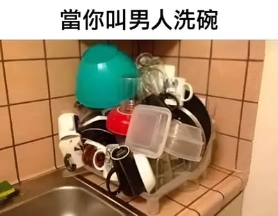 图片展示了一个厨房角落的碗碟架，里面堆满了各种未正确清洗或摆放的餐具，包括碗、杯子、保鲜盒等，显得非常杂乱无章。图片上方配有文字“當你叫男人洗碗”，通过展示混乱的餐具状态来幽默调侃男性洗碗不彻底或不认真的刻板印象。